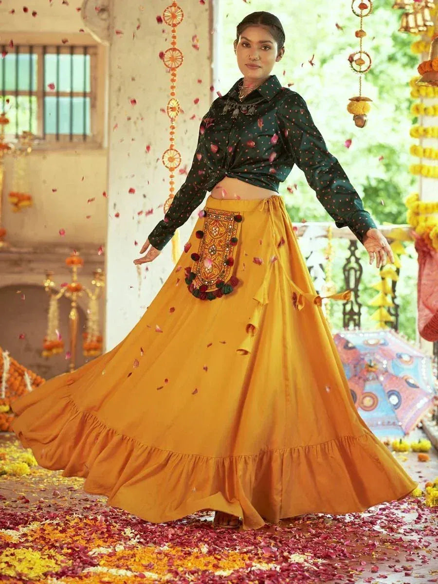 Woman in mustard yellow embroidered lehenga with black polka dot blouse, festive flower petals, traditional Indian wear