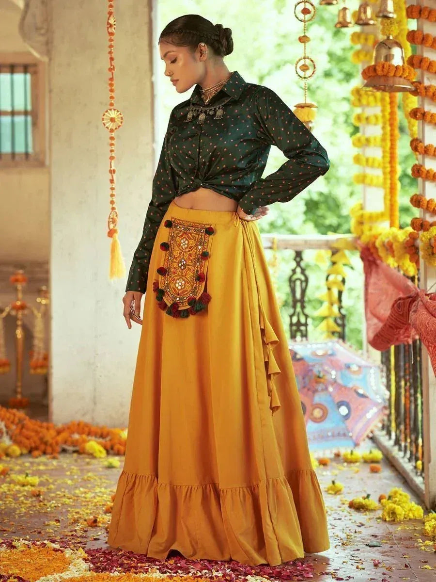 Woman in green polka dot crop top and mustard yellow embroidered lehenga skirt, festive Indian ethnic wear