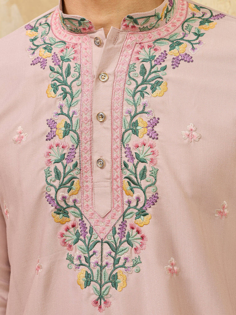 Close-up of a light pink men's ethnic kurta with colorful floral embroidery on the neckline
