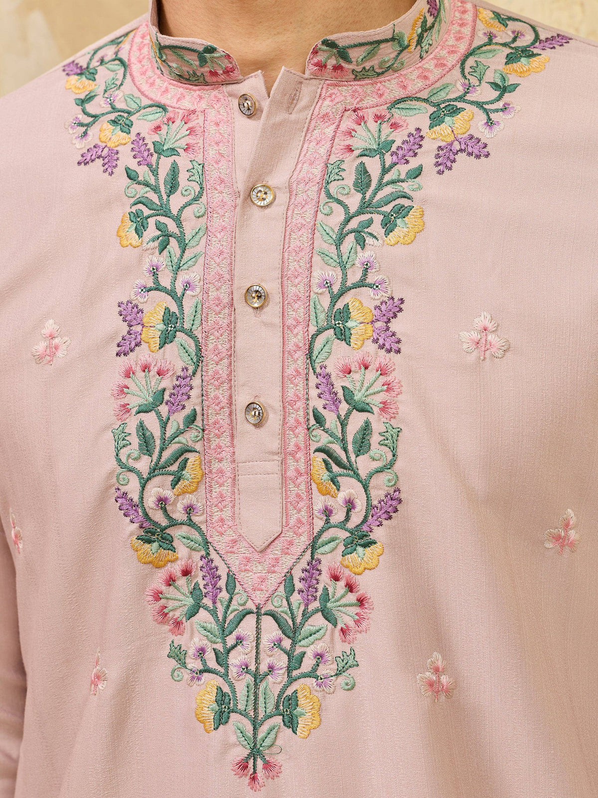 Close-up of a light pink men's ethnic kurta with colorful floral embroidery on the neckline