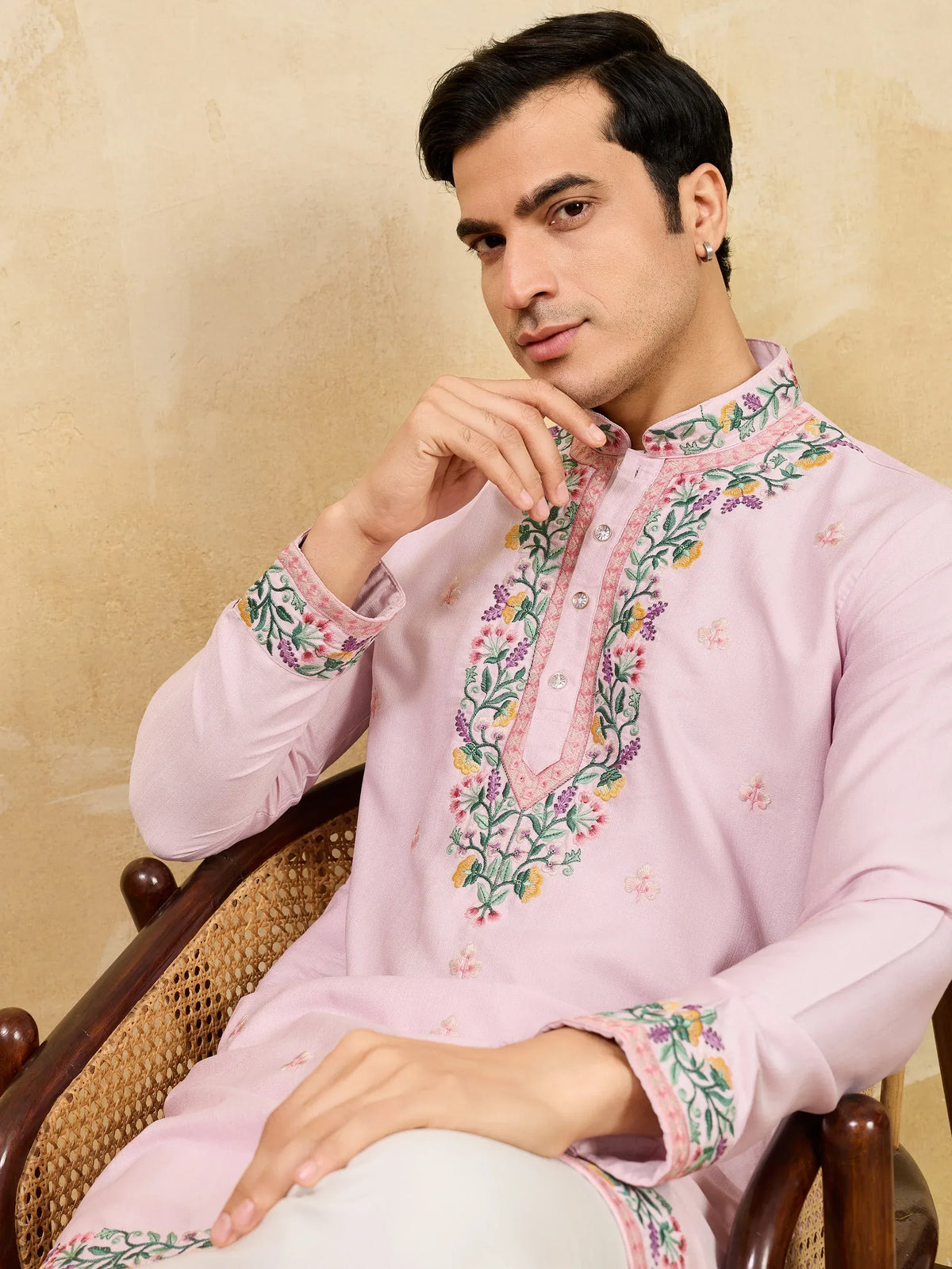 Man wearing a light pink embroidered ethnic kurta with floral details.