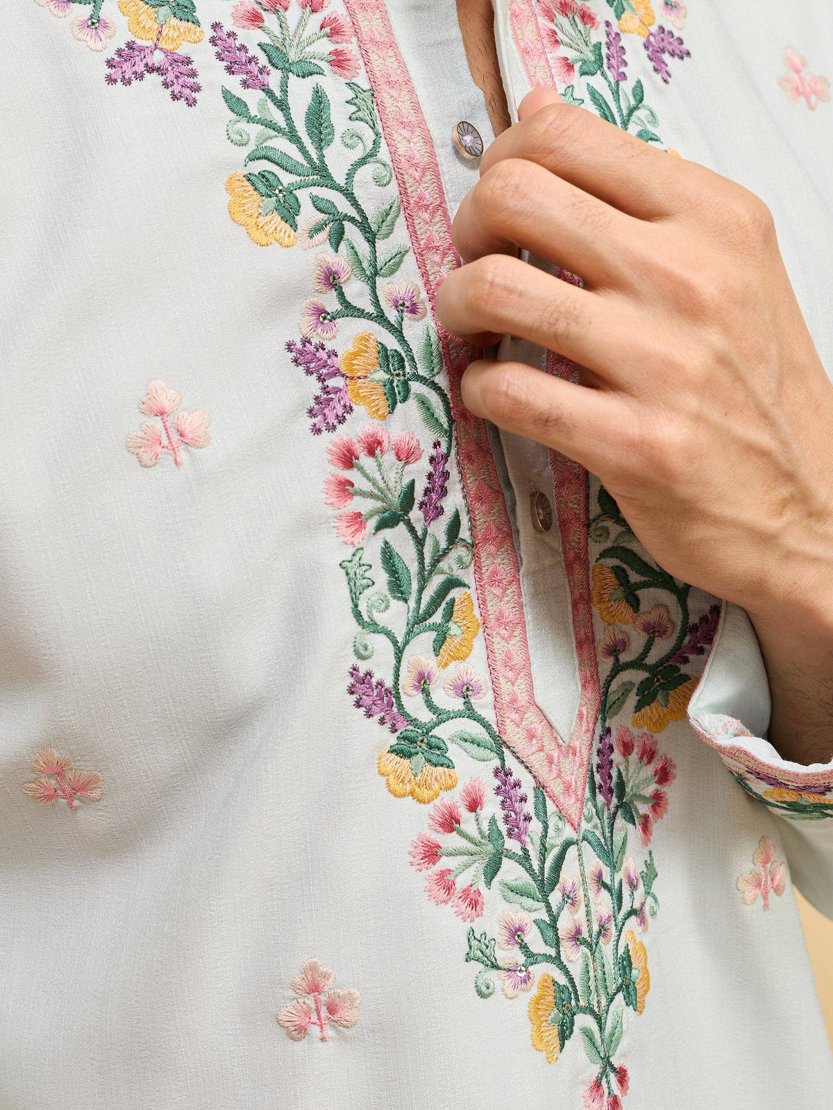 Close-up of a white men's kurta with colorful floral embroidery around the neckline