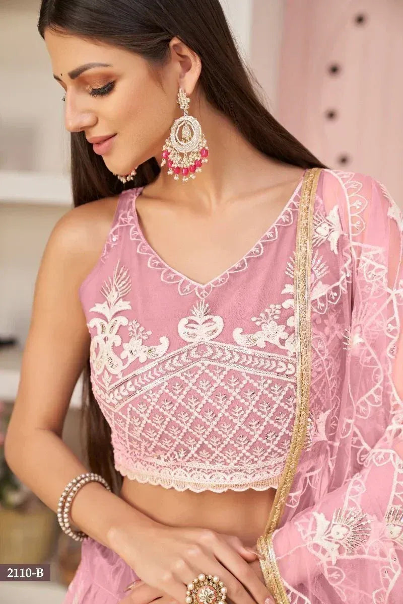 Pink embroidered lehenga choli with white lace and gold trim, paired with statement earrings