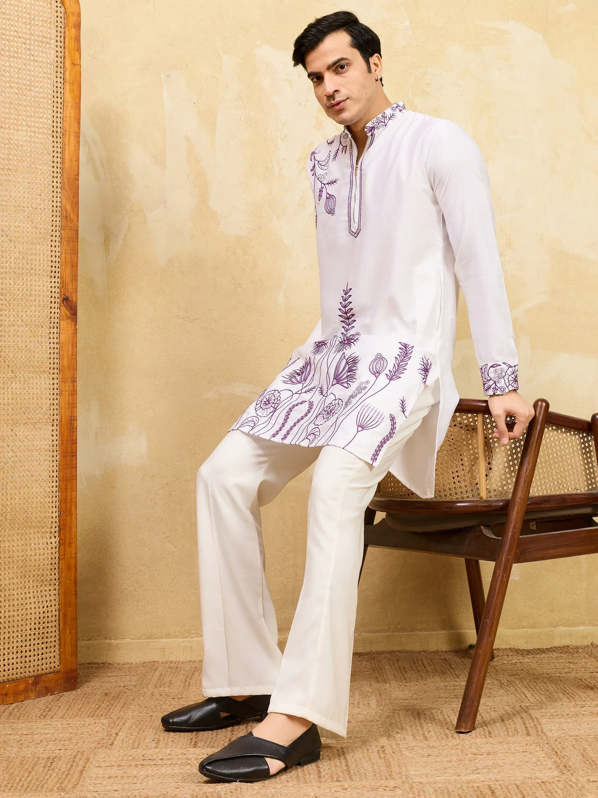 Man wearing a white embroidered kurta and pants with black traditional footwear