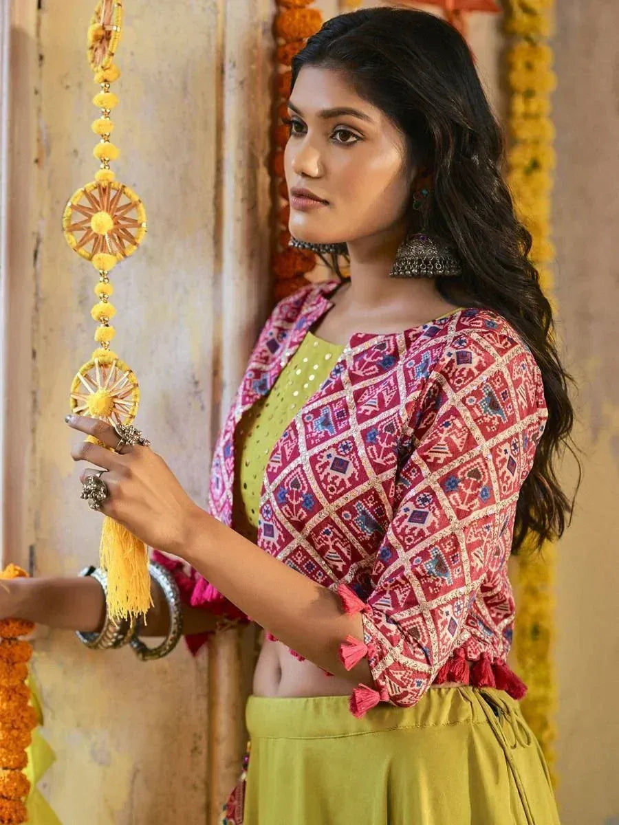 Woman in vibrant red printed blouse with tassels and green palazzo, styled with ethnic jewelry and marigold decor