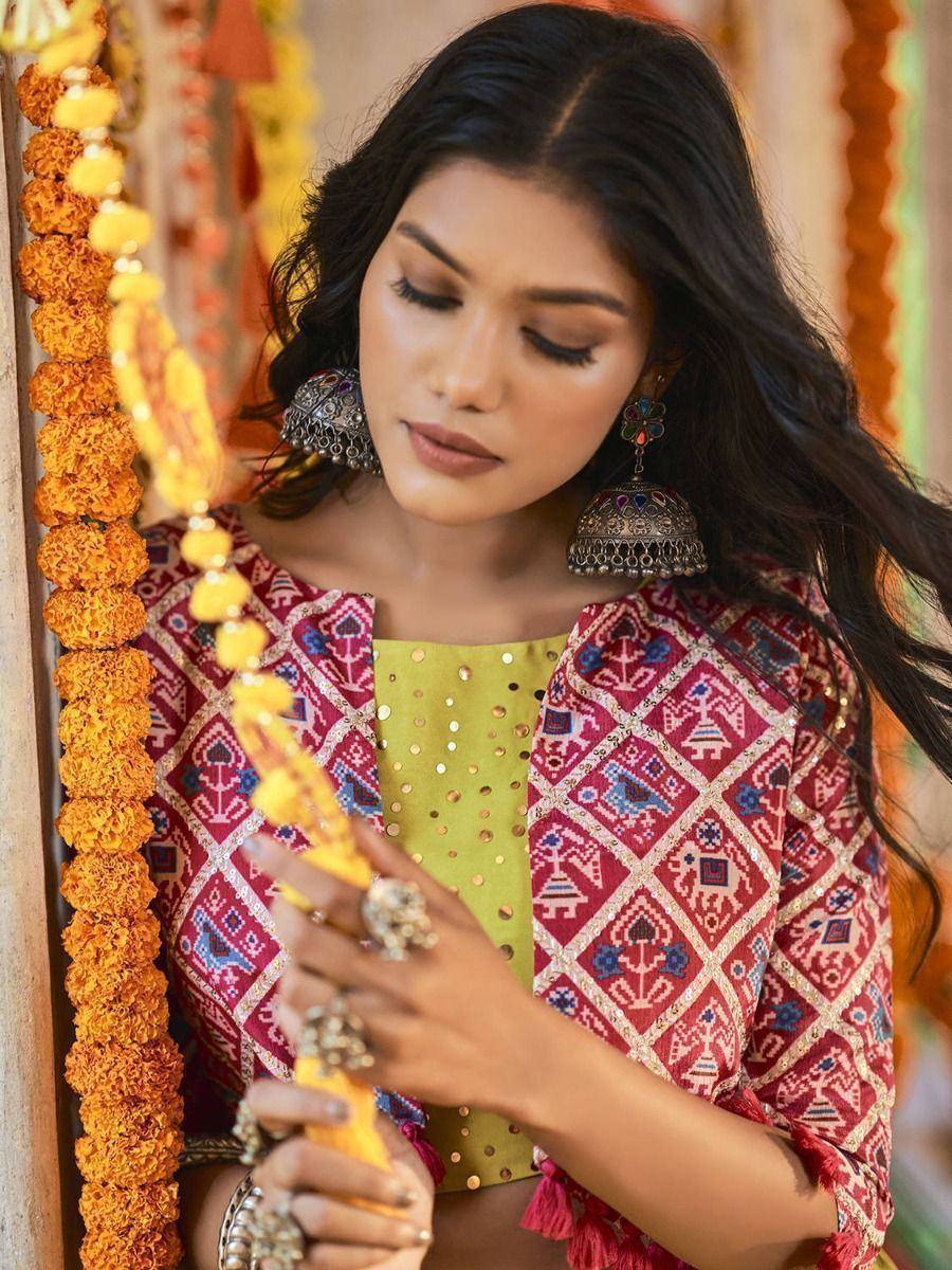 Woman in red printed ethnic top with gold sequin blouse, marigold garlands, and jhumka earrings