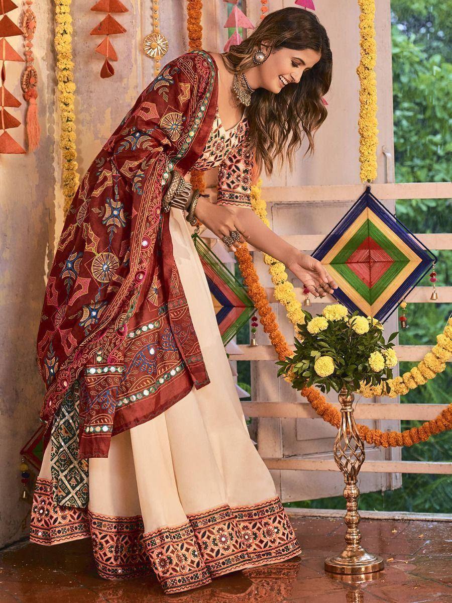 Woman in embroidered maroon and cream Indian ethnic wear, festive decor, floral garlands