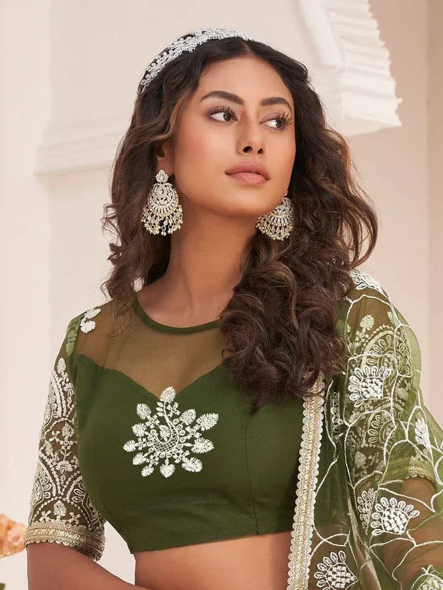 Olive green embroidered lehenga choli with sheer sleeves and floral detailing, paired with statement earrings.