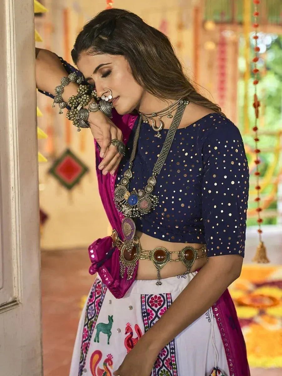 Woman in navy blue sequin crop top with white embroidered skirt, pink dupatta, and traditional Indian jewelry