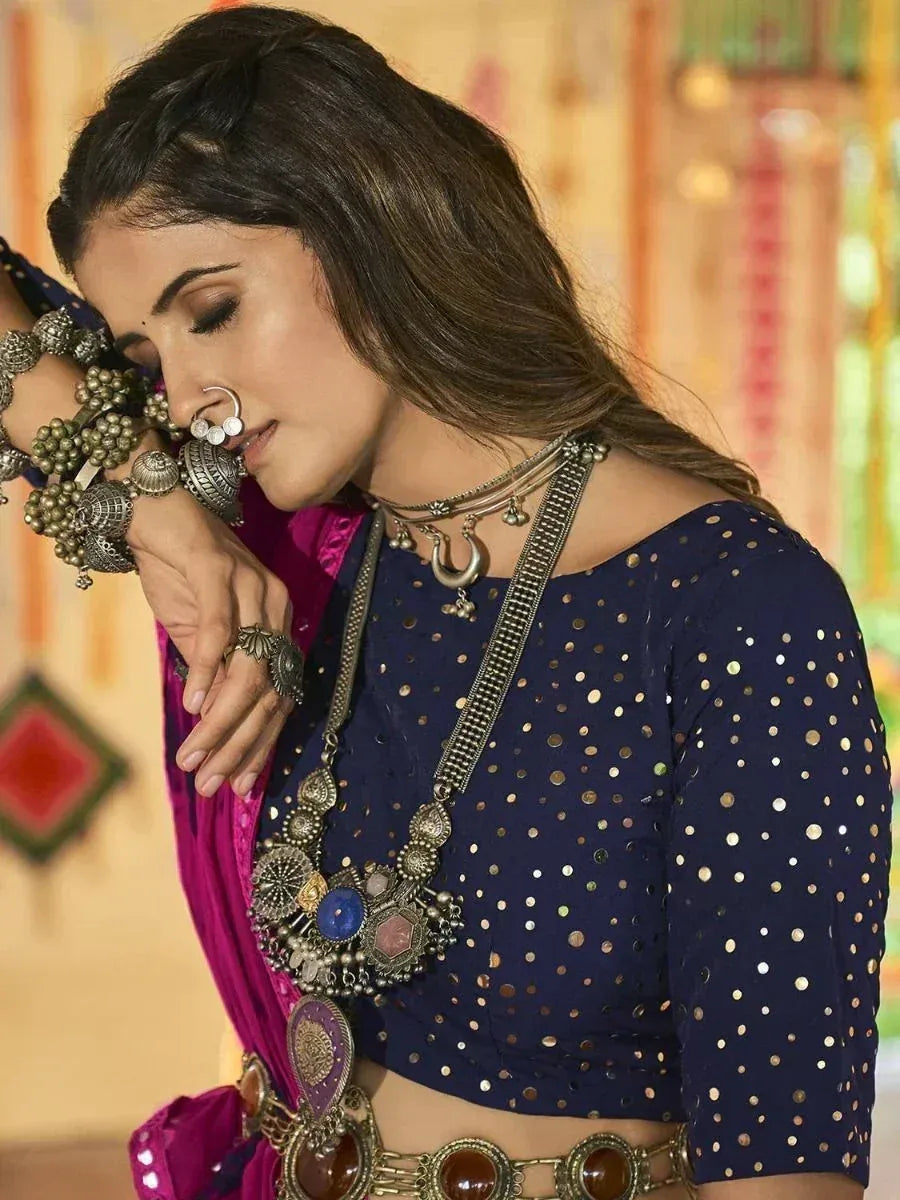 Woman in navy blue sequin blouse with pink saree, traditional Indian jewelry, and nose ring