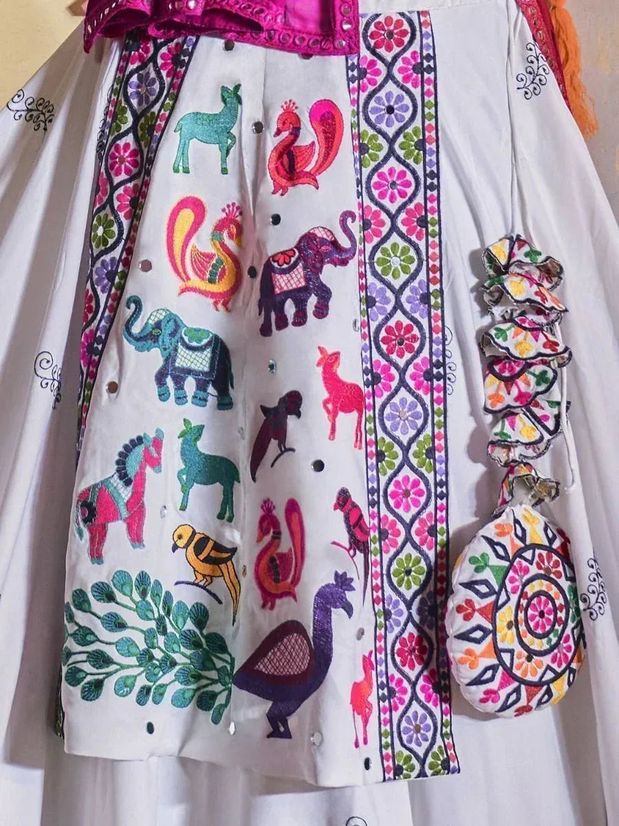 White ethnic gown with colorful animal embroidery, floral borders, and matching potli bag for festive occasions