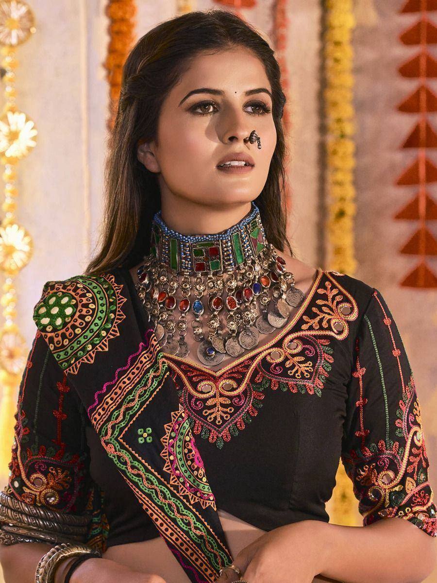 Black embroidered ethnic top with colorful mirror work, paired with statement jewelry for Indian festive wear.