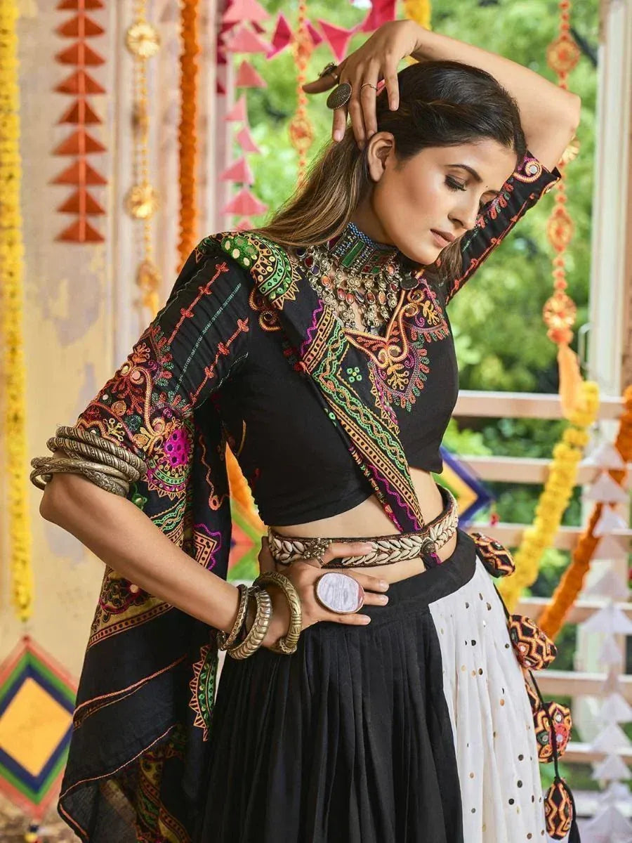 Woman in black embroidered ethnic crop top and skirt with colorful mirror work, perfect for festive occasions.