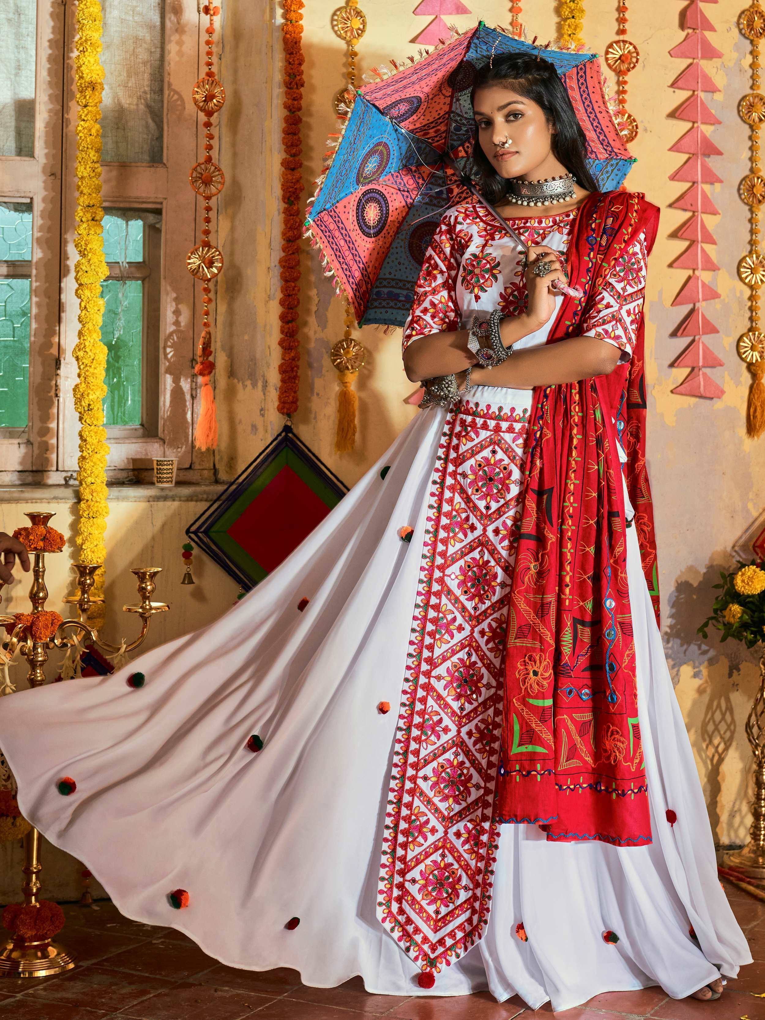Woman in embroidered white and red ethnic gown with colorful umbrella, festive Indian decor