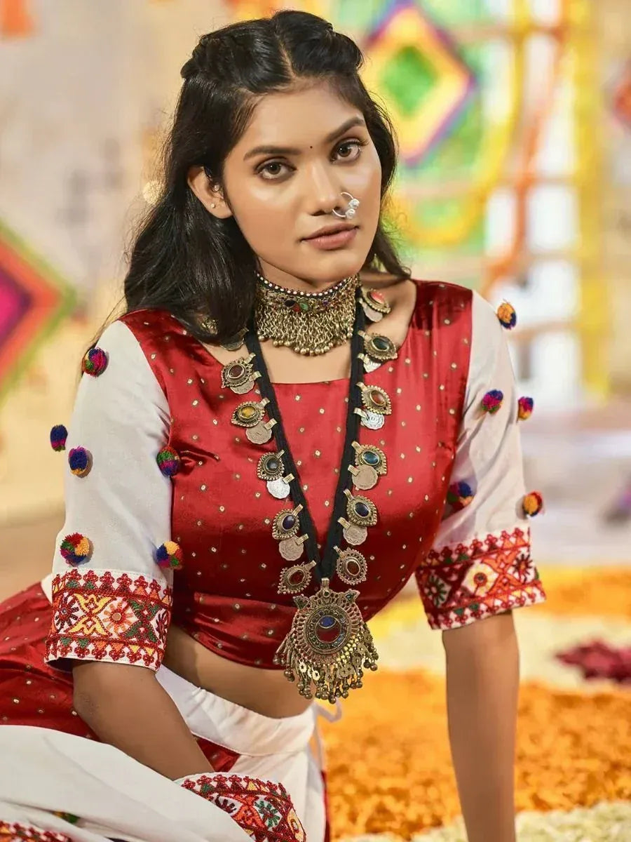 Woman in red and white ethnic Indian outfit with embroidered sleeves and traditional jewelry