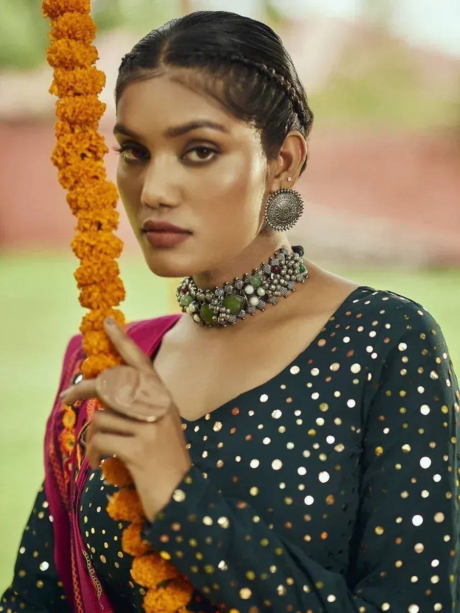 Woman in black sequin ethnic top with marigold garland, traditional Indian jewelry, and pink dupatta