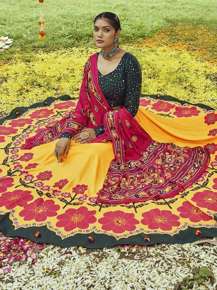 Woman in vibrant floral print Indian ethnic salwar kameez with mirror work, sitting on grass