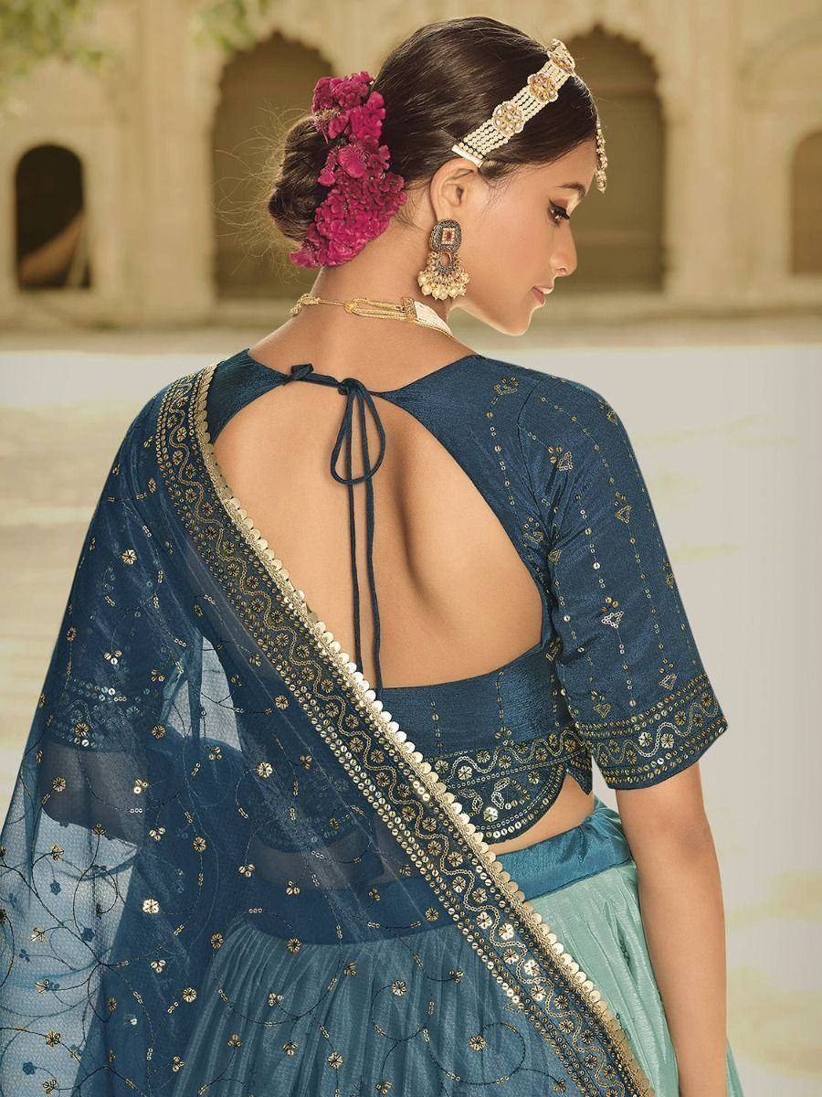 Blue embroidered lehenga choli with back tie detail, gold embellishments, and floral hair accessory