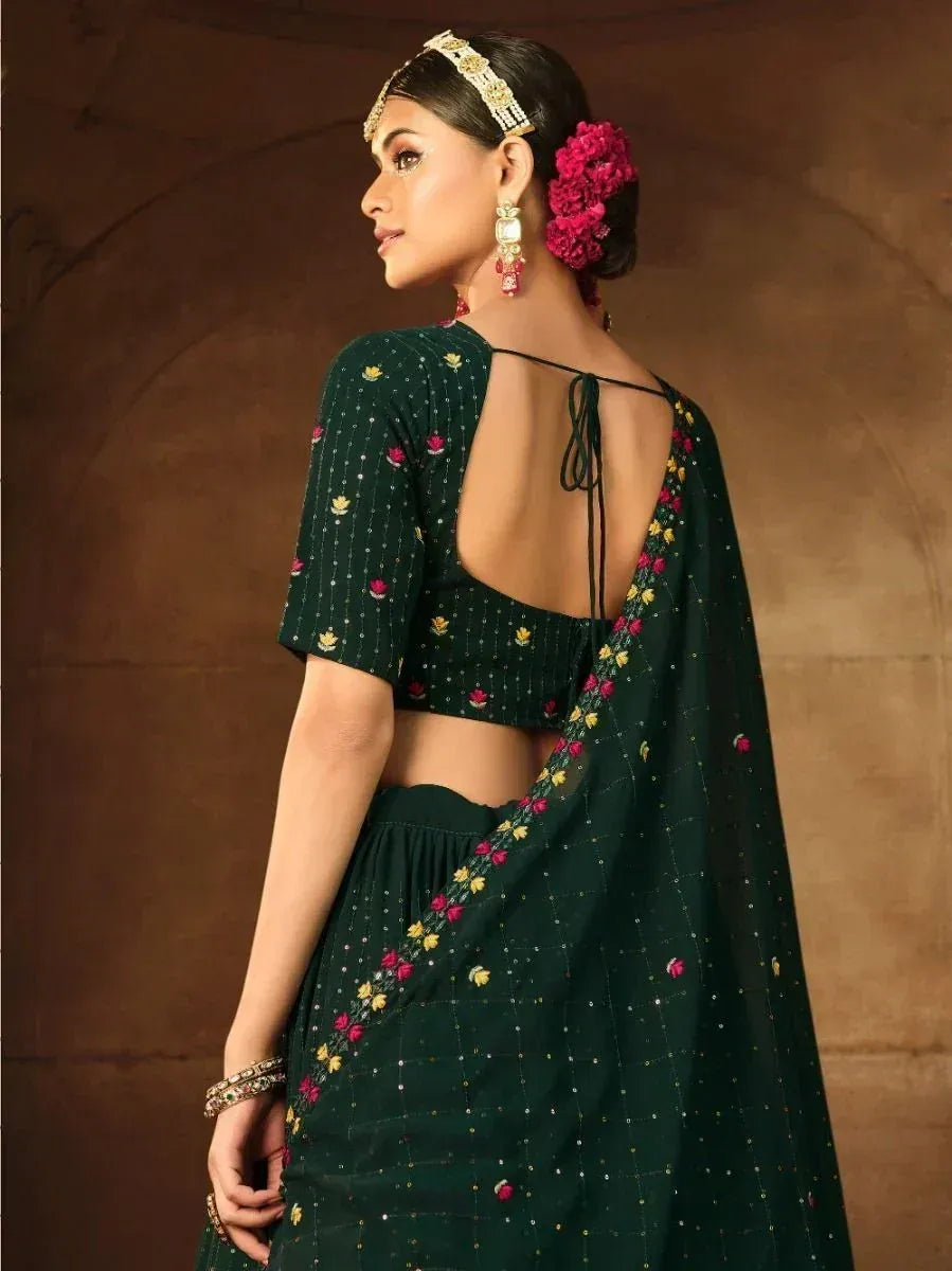 Emerald green embroidered lehenga choli with open back, floral motifs, and traditional jewelry for Indian ethnic wear.