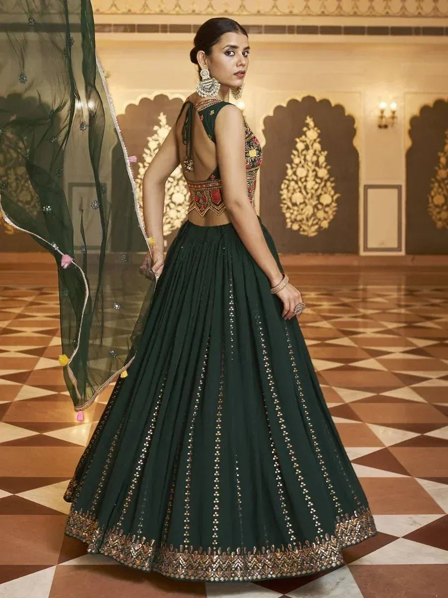 Emerald green designer lehenga choli with gold embroidery, backless blouse, and sheer dupatta for Indian ethnic wear.