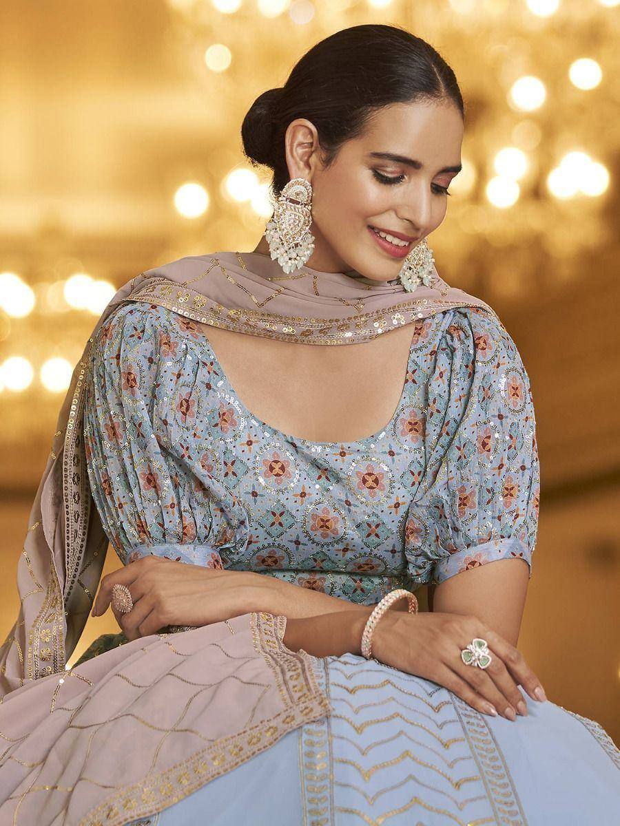 Elegant light blue floral lehenga choli with gold embroidery, paired with matching dupatta and statement earrings
