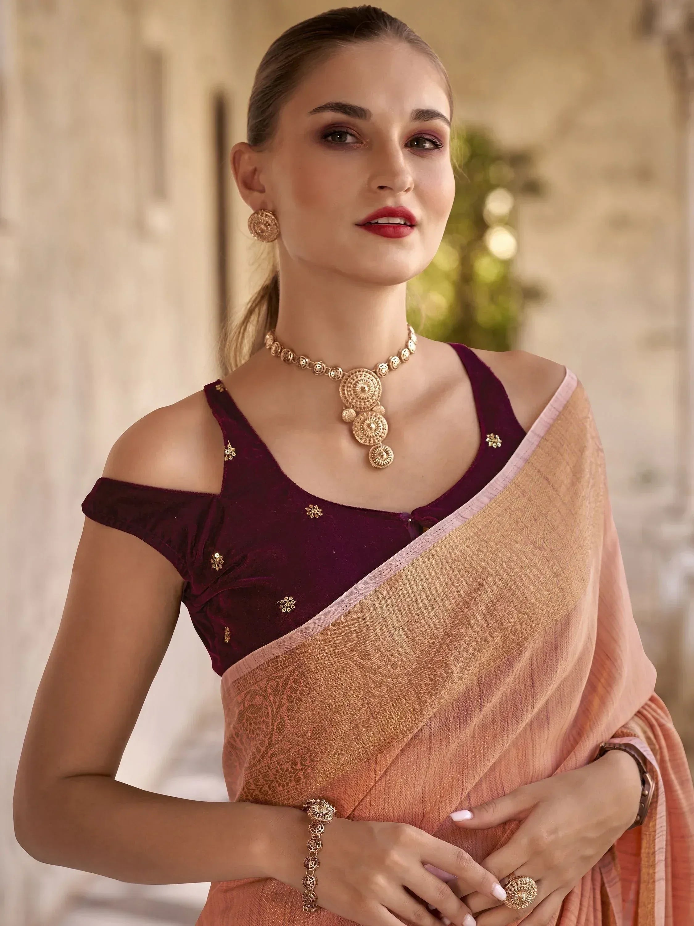 Woman in peach saree with maroon velvet blouse, gold jewelry, traditional Indian ethnic wear