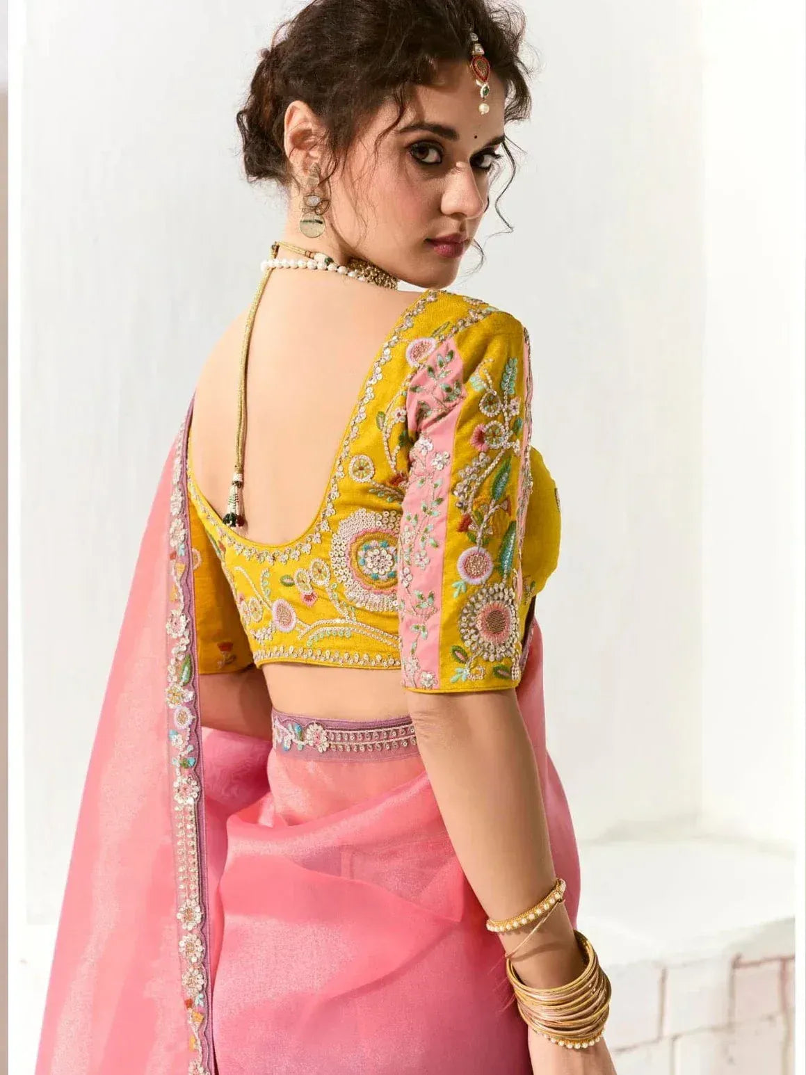 Yellow embroidered blouse with pink saree, floral detailing, and backless design for ethnic wear