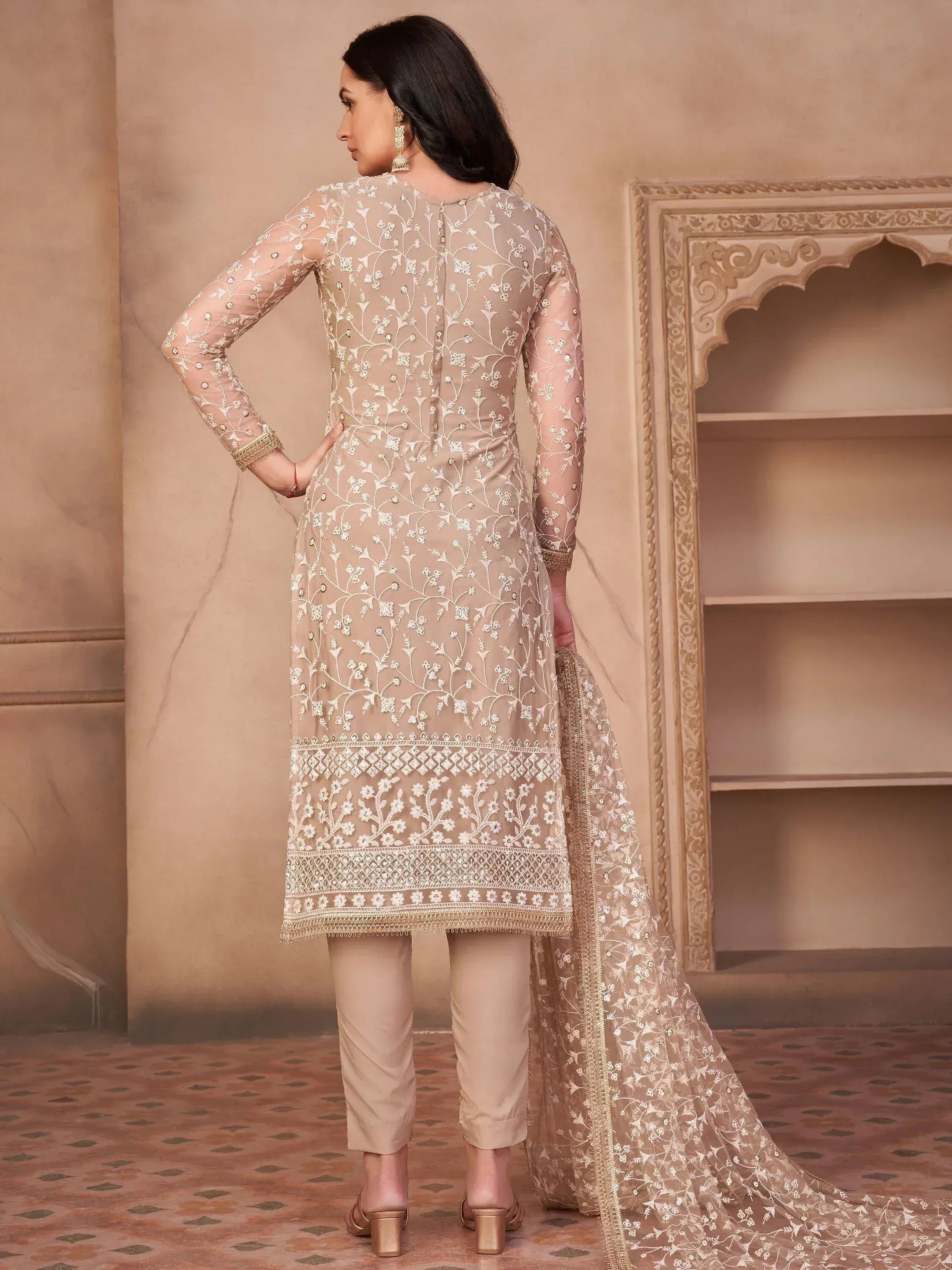 Woman wearing beige embroidered Indian salwar kameez with matching dupatta, back view
