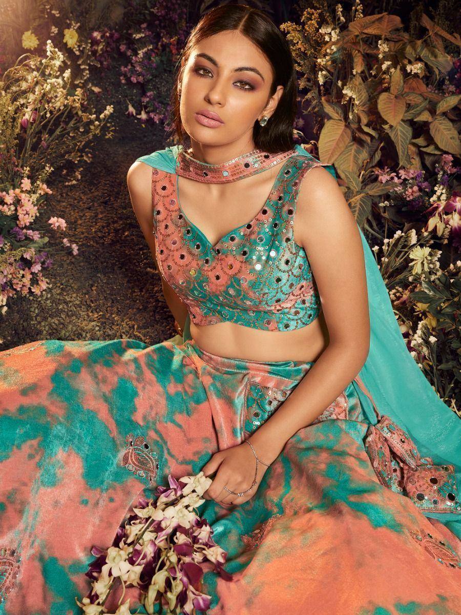 Teal and coral designer lehenga choli with mirror work, floral backdrop, ethnic wear