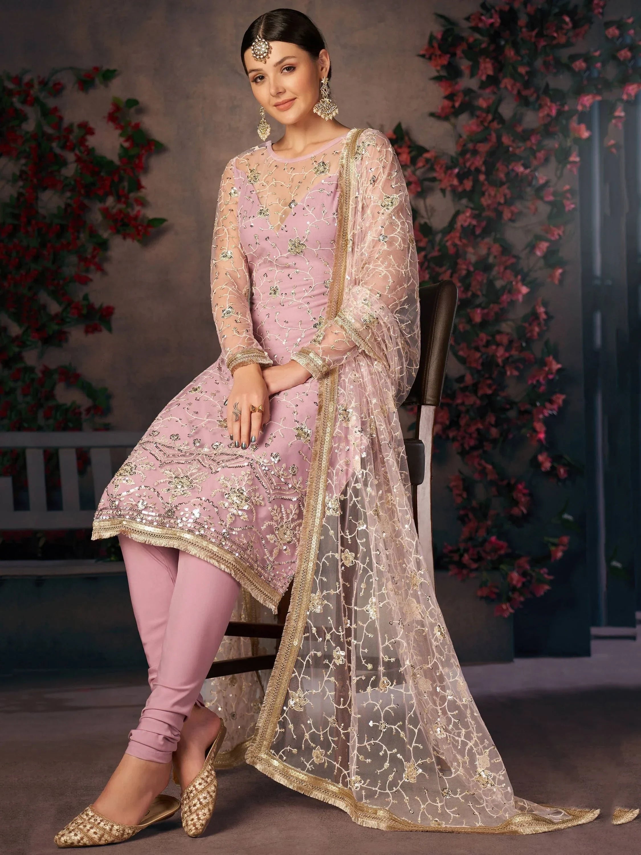 Woman in a pastel pink embroidered salwar kameez with sheer dupatta and ethnic jewelry