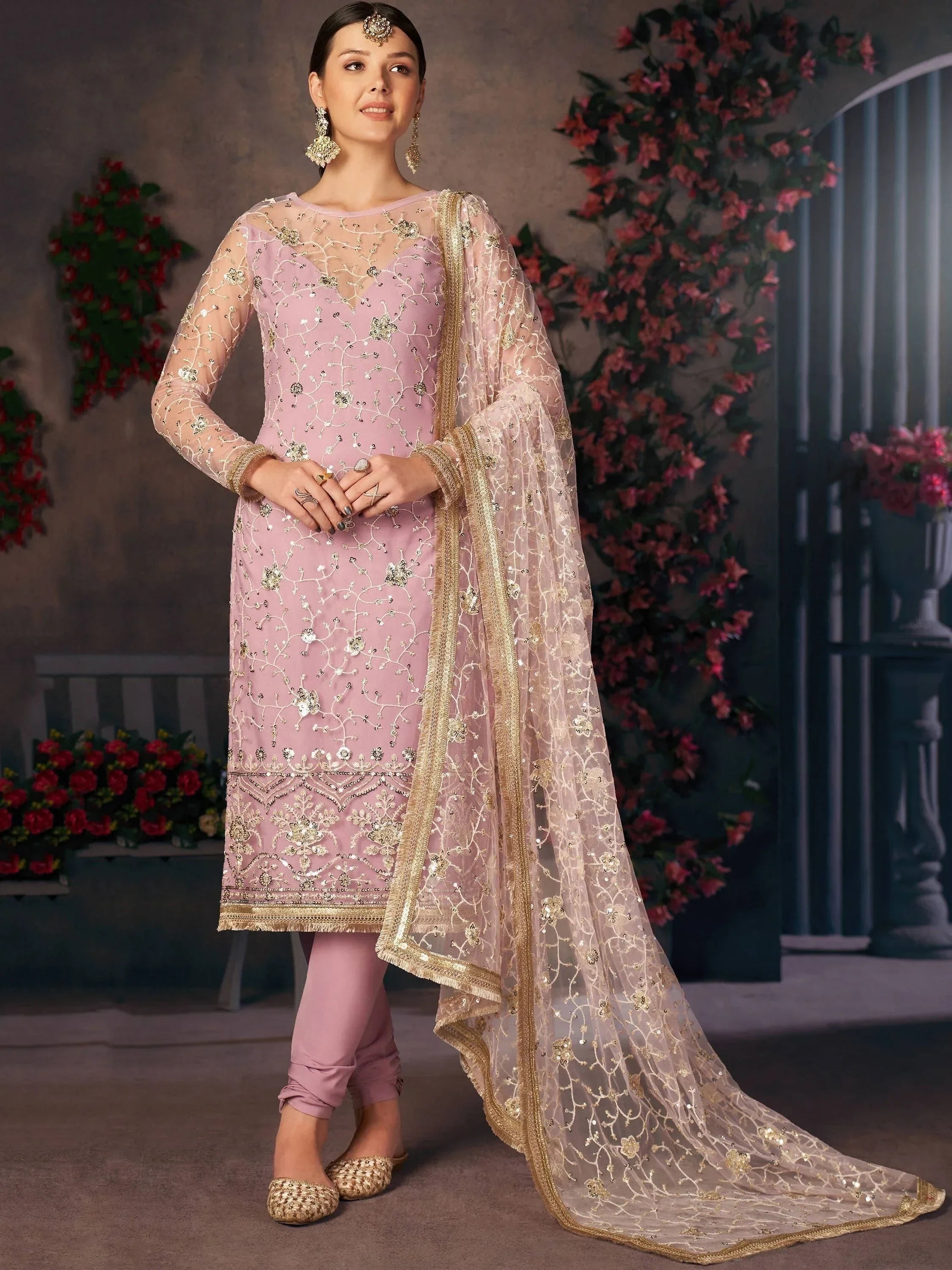 Woman in pastel pink embroidered salwar kameez with net dupatta and gold jewelry