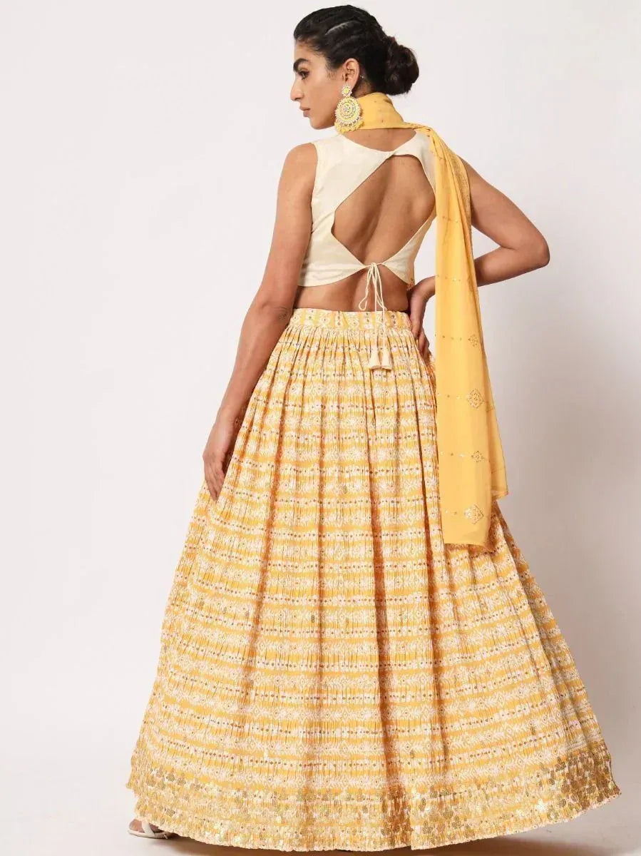 Yellow printed lehenga with backless cream blouse and matching dupatta, ethnic Indian wear