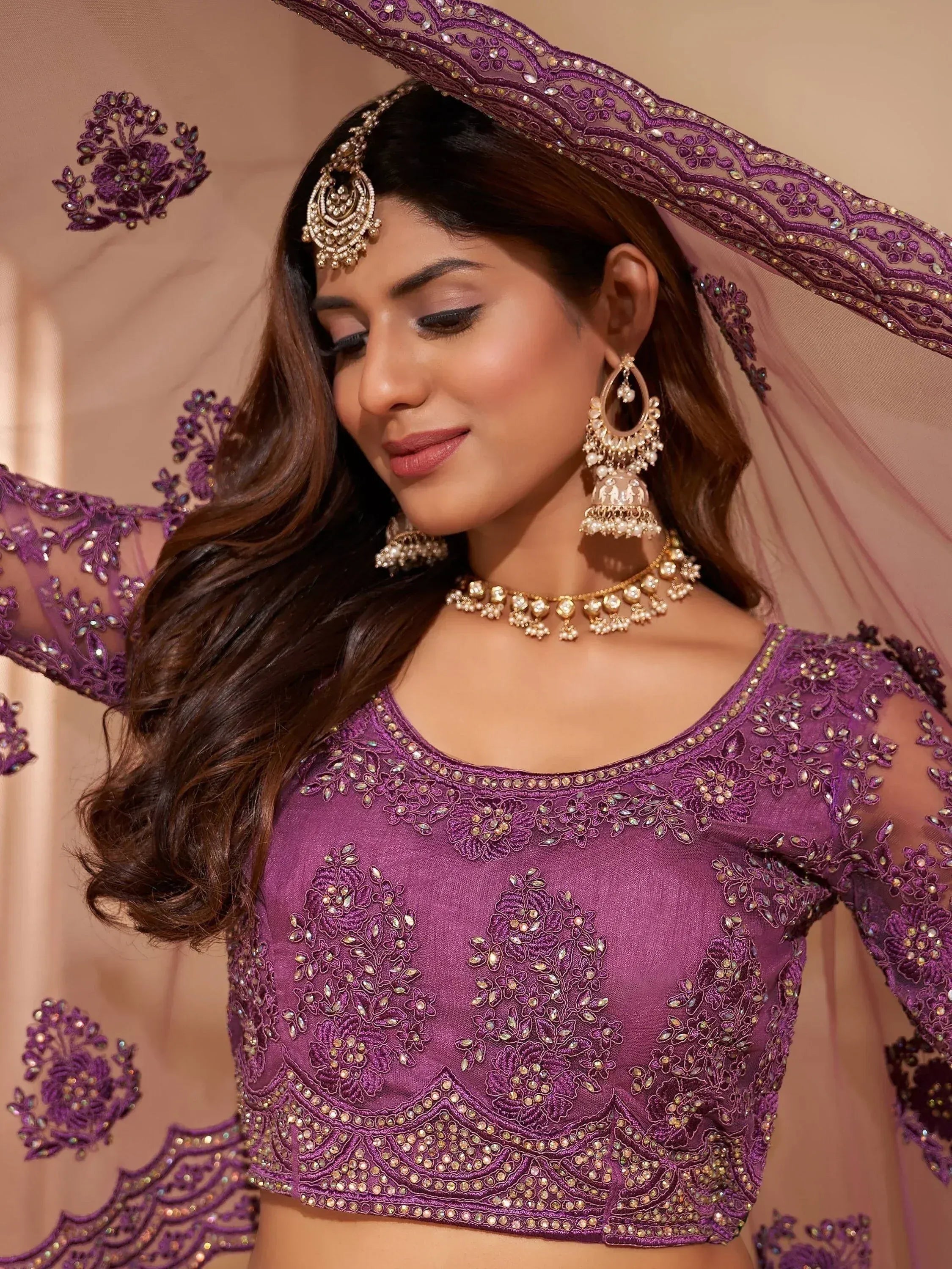 Purple embroidered lehenga choli with sheer sleeves, matching dupatta, and traditional Indian jewelry