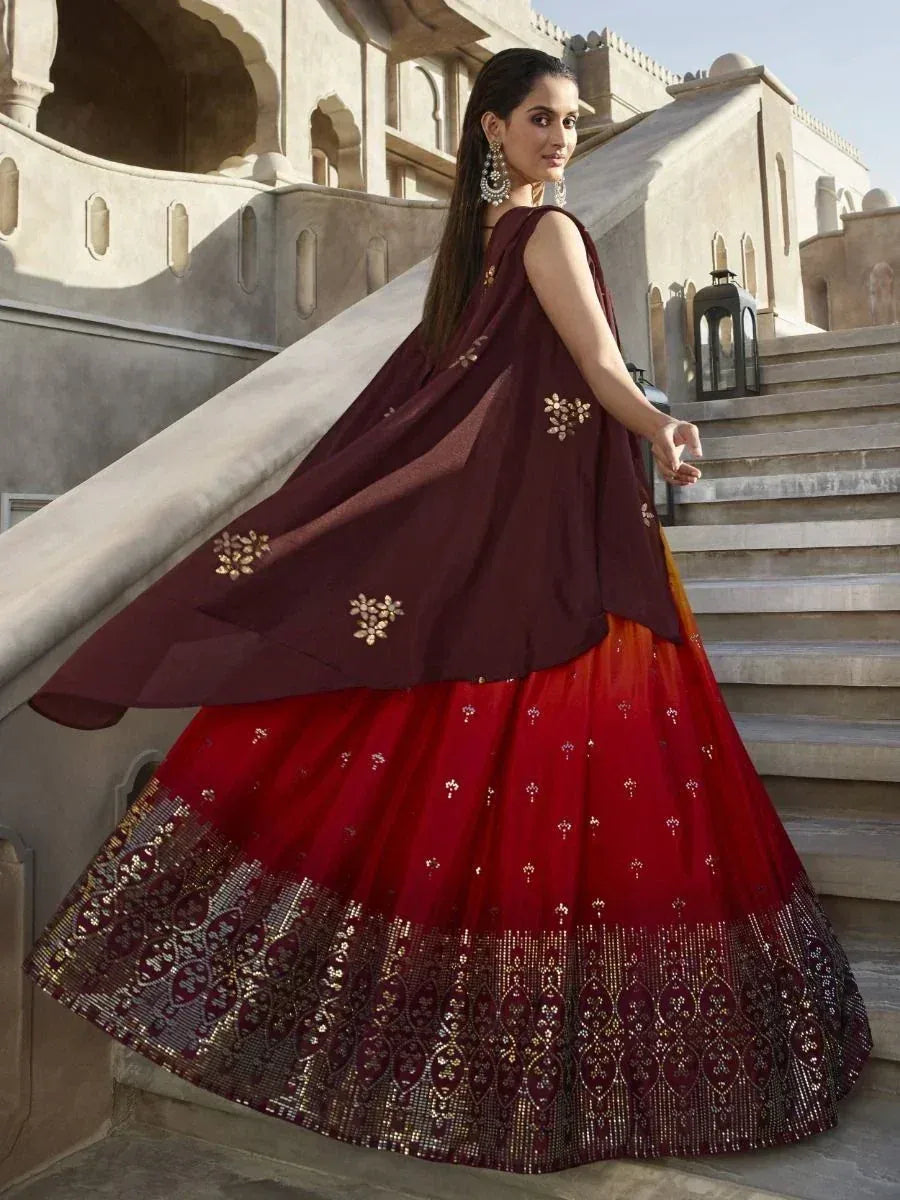 Maroon and red embroidered lehenga choli with gold detailing, styled on stairs near palace architecture