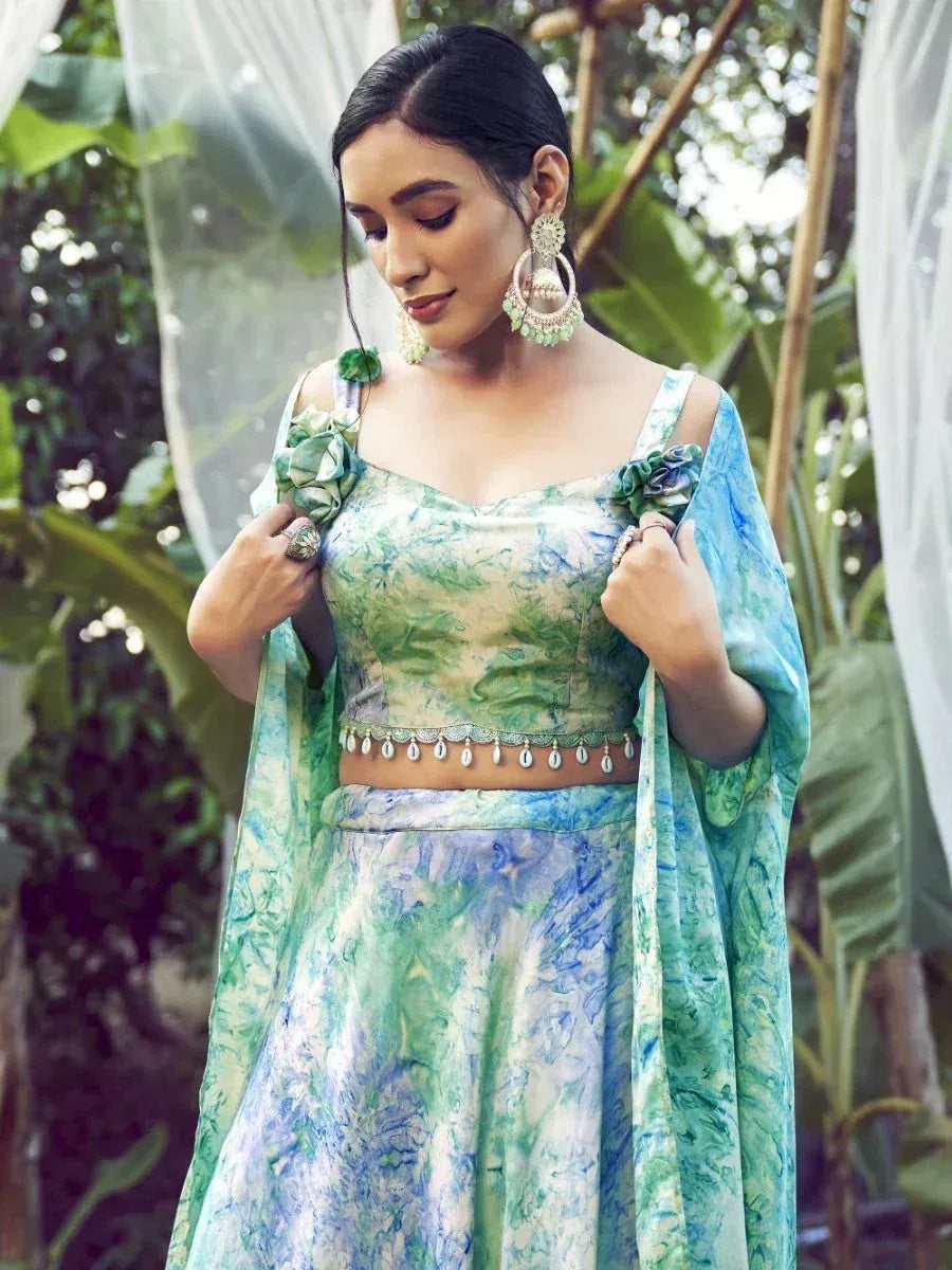 Green and blue printed lehenga choli with floral embellishments and statement earrings