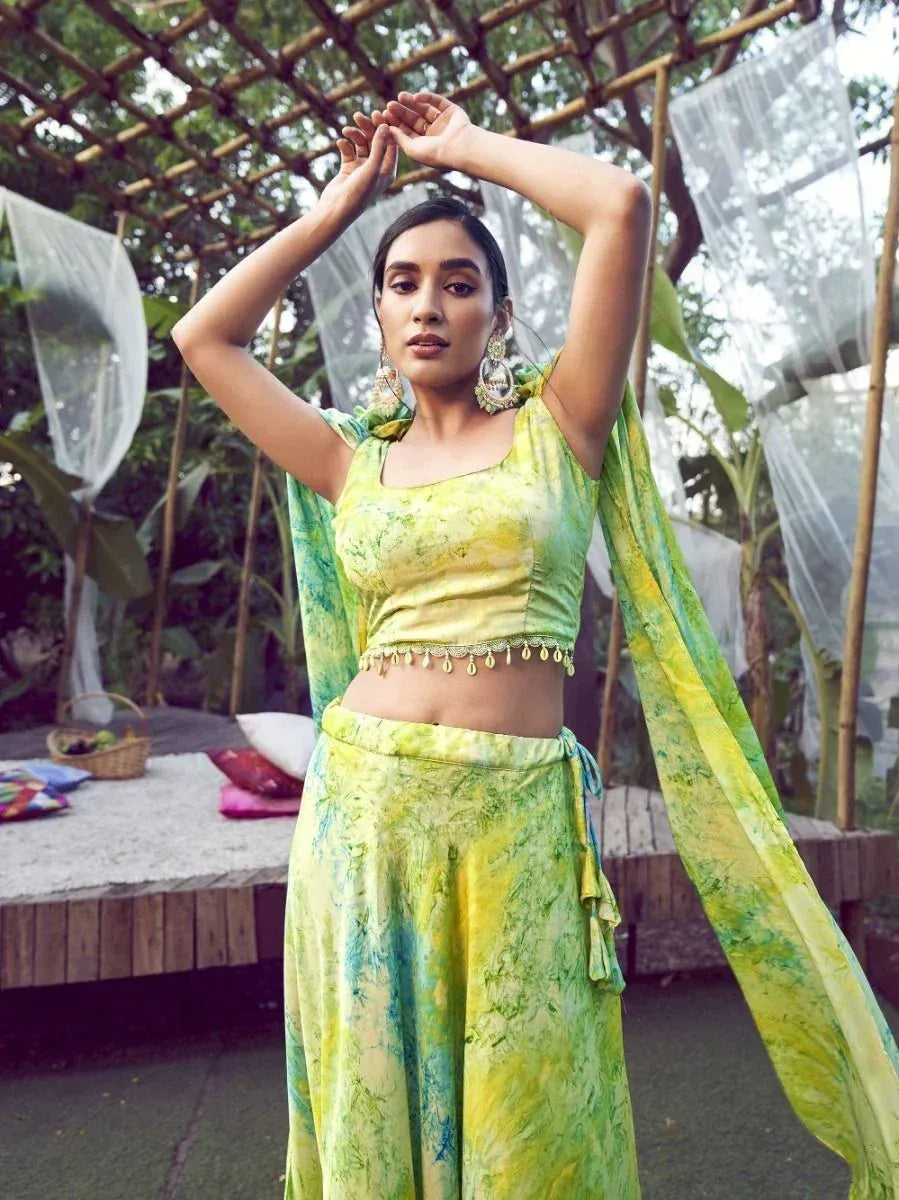 Woman in vibrant green-yellow tie-dye ethnic crop top and palazzo pants with dupatta, styled for Indian festive wear.