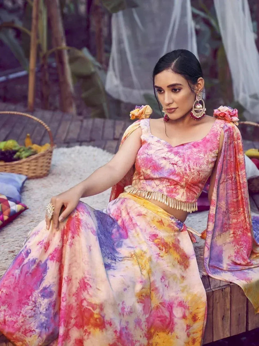 Woman in vibrant tie-dye lehenga choli with floral shoulder details, perfect for ethnic occasions