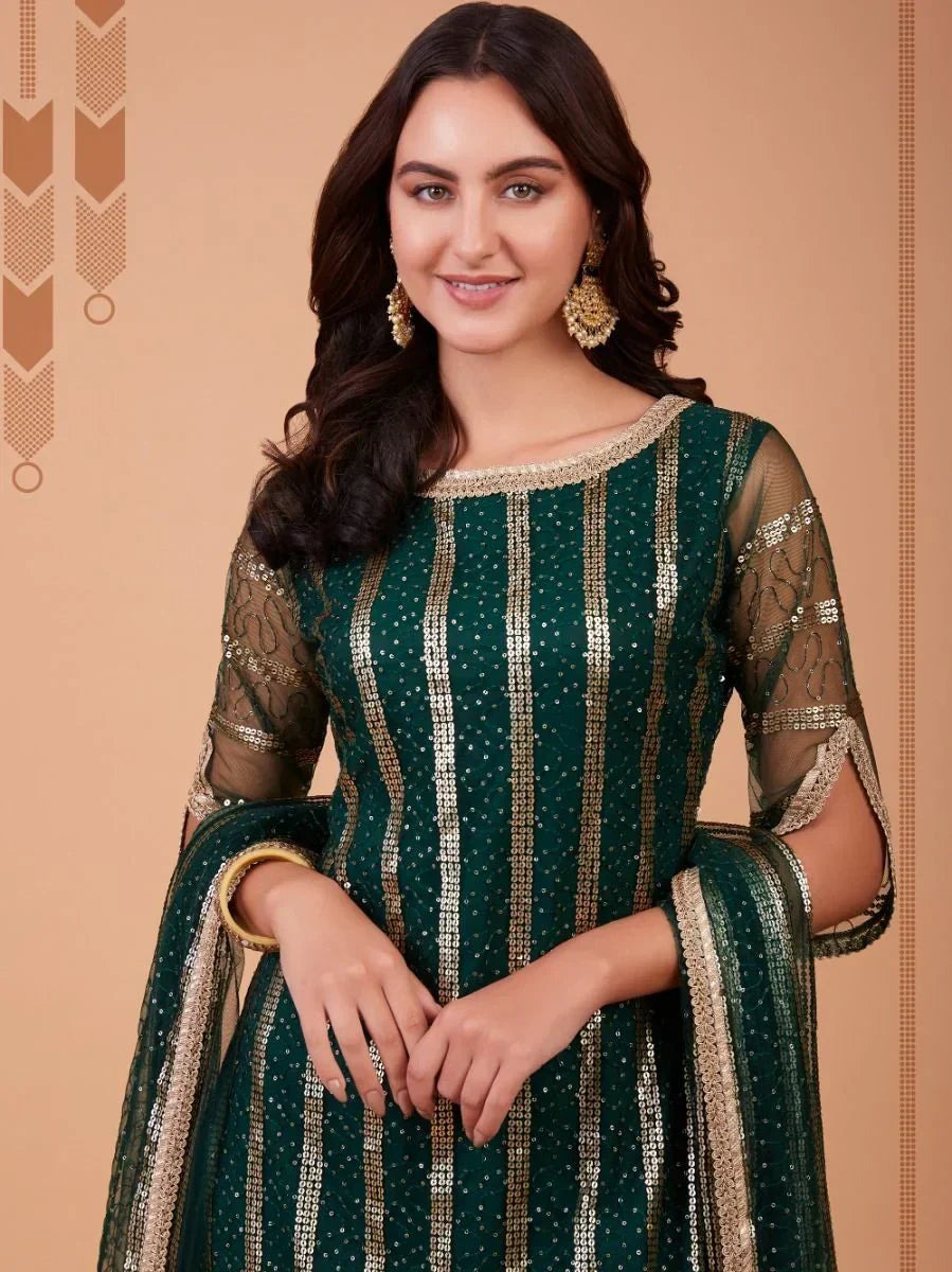 Woman in a green and gold embroidered ethnic gown with sheer sleeves and gold jewelry