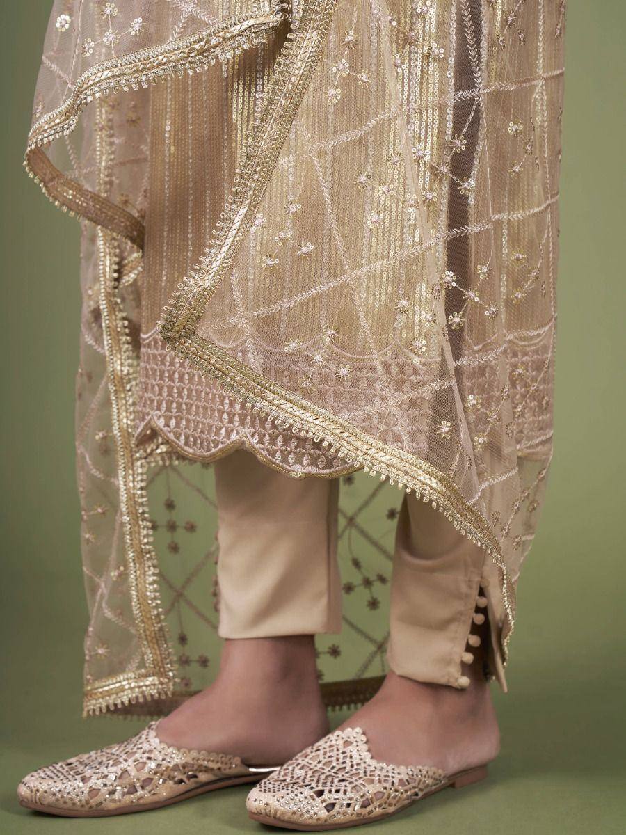 Beige embroidered salwar kameez with gold detailing and matching juttis, perfect for ethnic occasions.