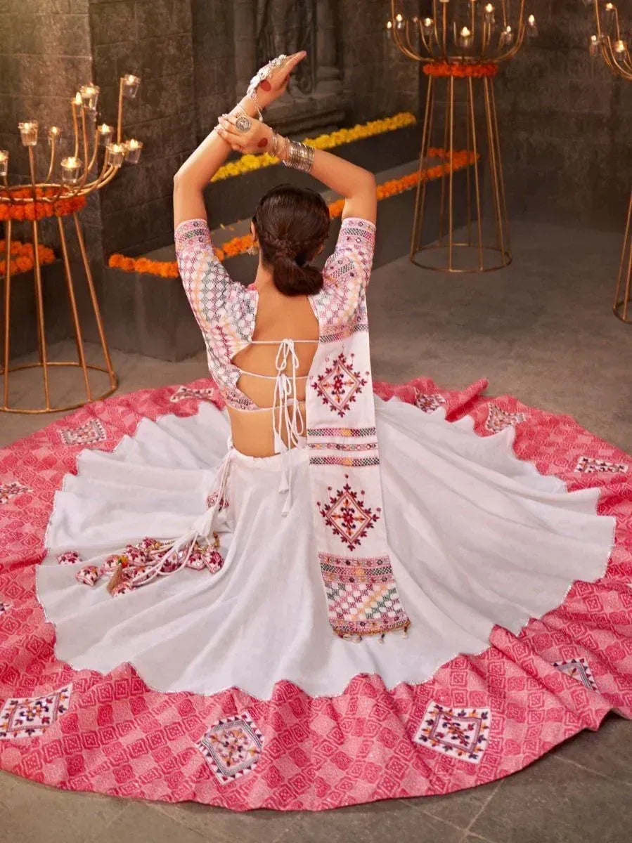 Woman in white and pink embroidered lehenga choli with open back, dancing in festive setting