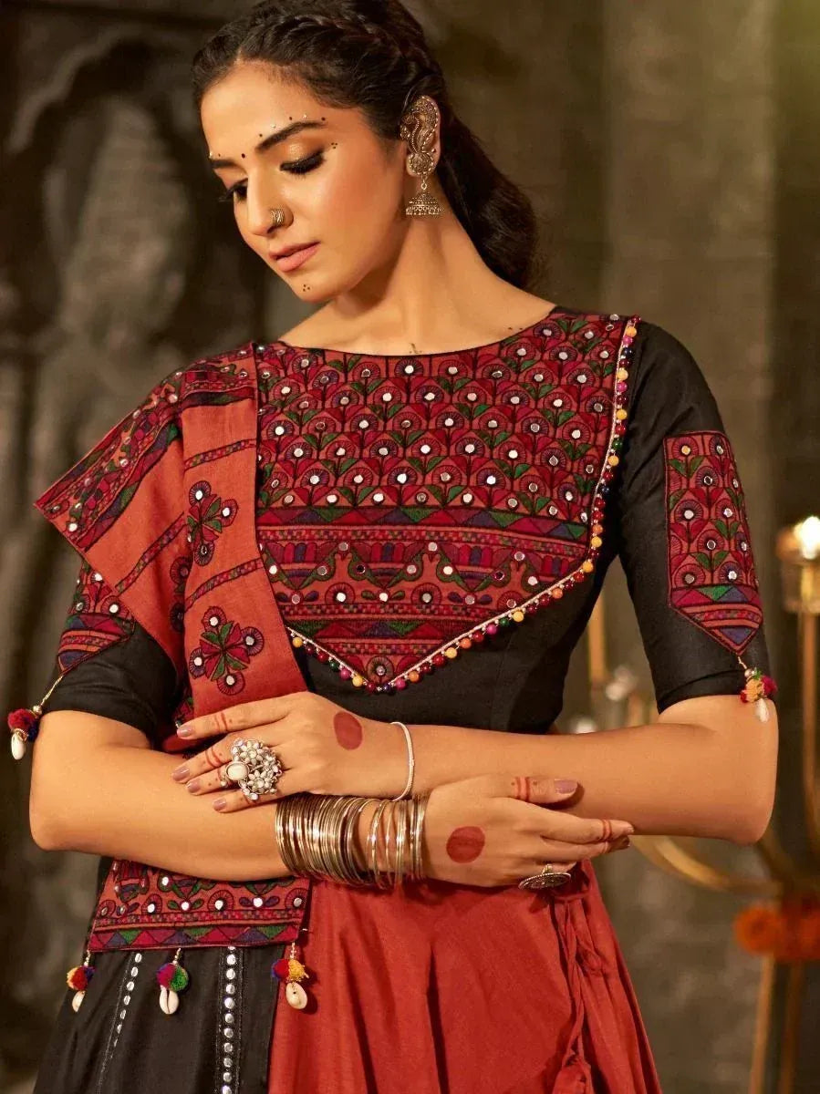 Woman in embroidered ethnic salwar kameez with mirror work and pom-pom details, styled with traditional jewelry