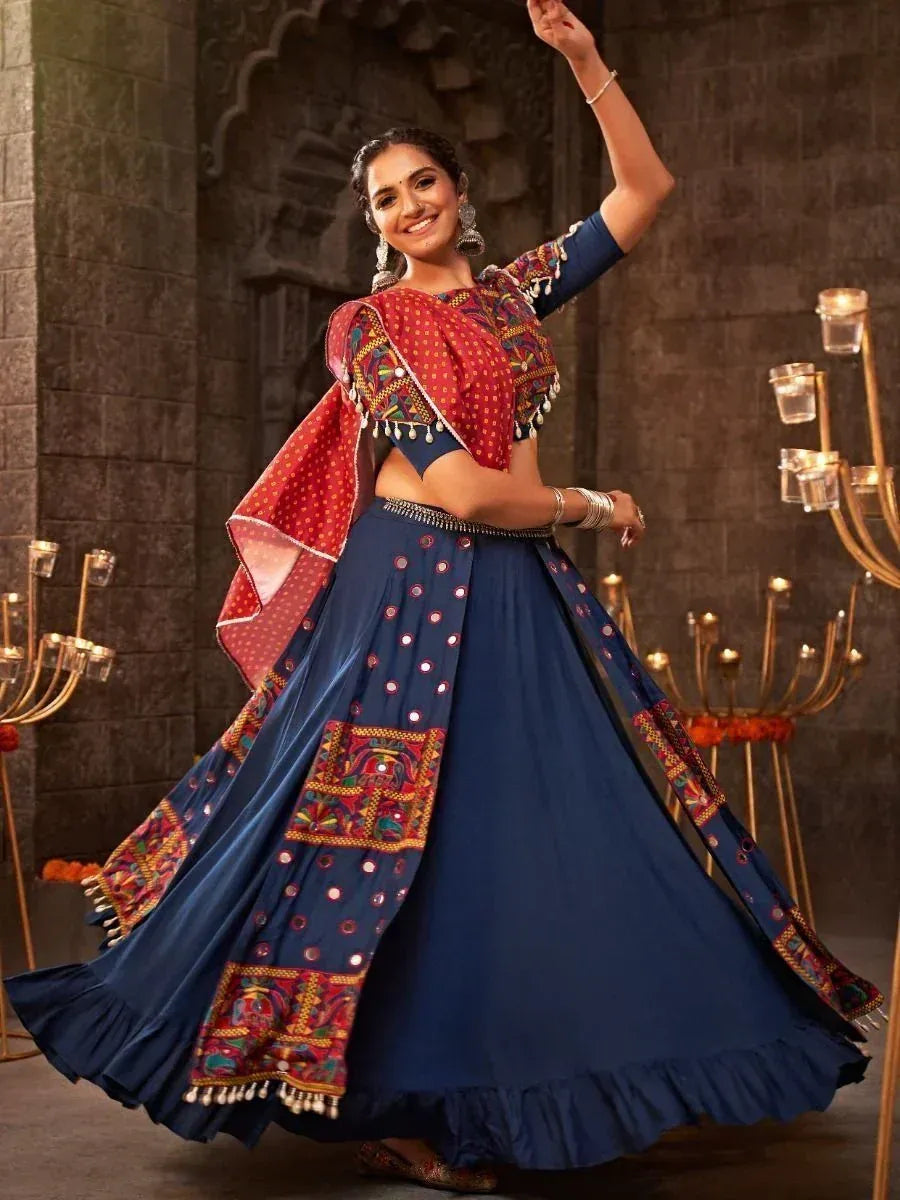 Woman in blue embroidered lehenga choli with red dupatta, dancing in traditional Indian ethnic wear