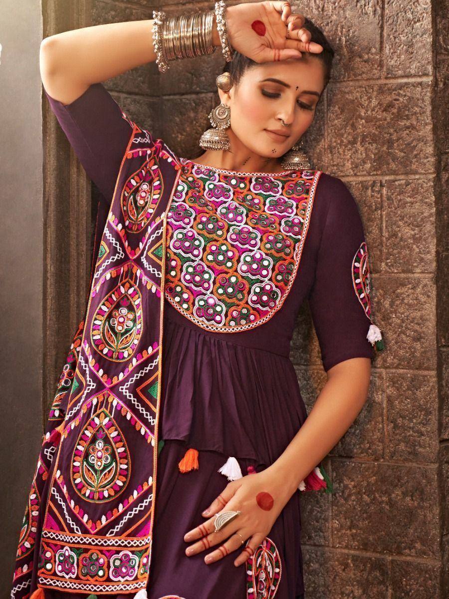 Purple embroidered ethnic gown with colorful mirror work and tassels, styled with traditional jewelry