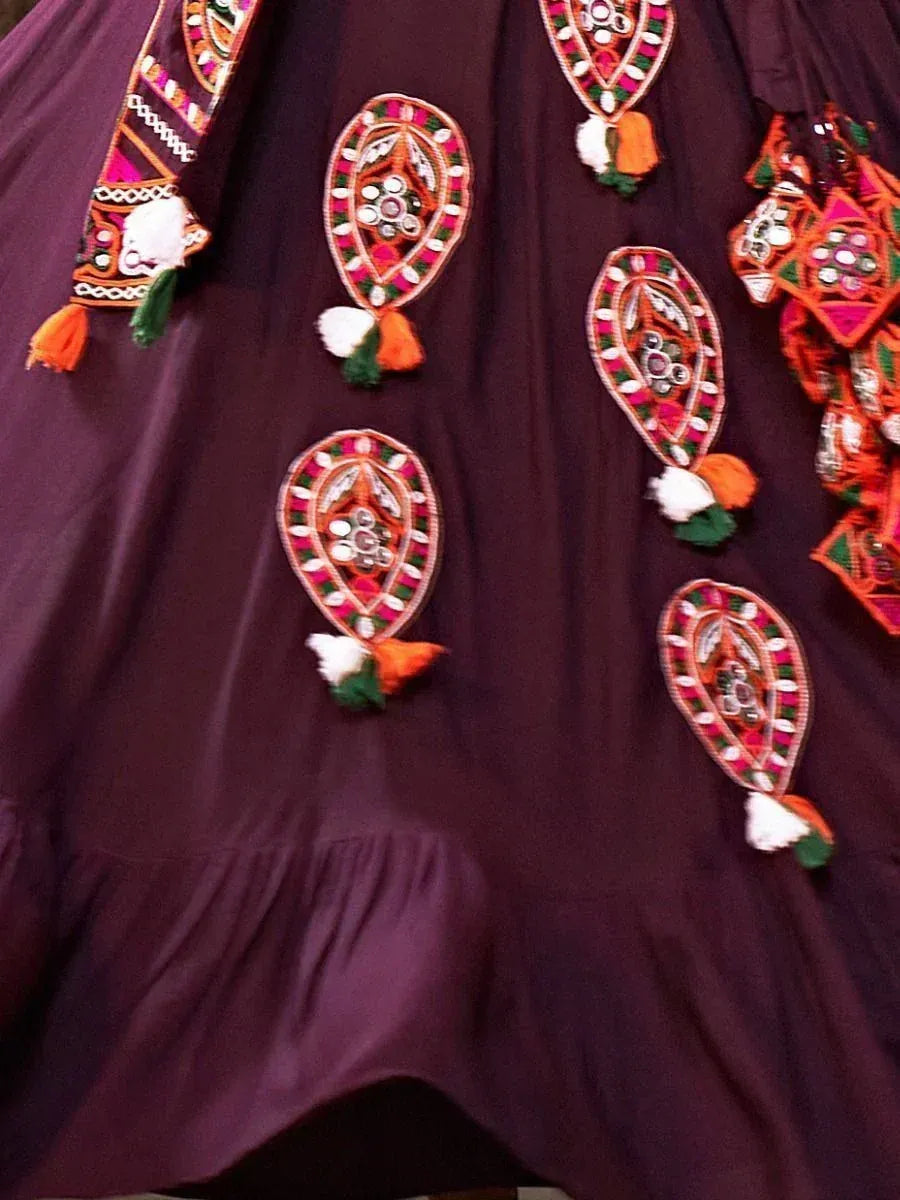 Purple ethnic gown with colorful mirror work and tassels, perfect for Indian festive occasions