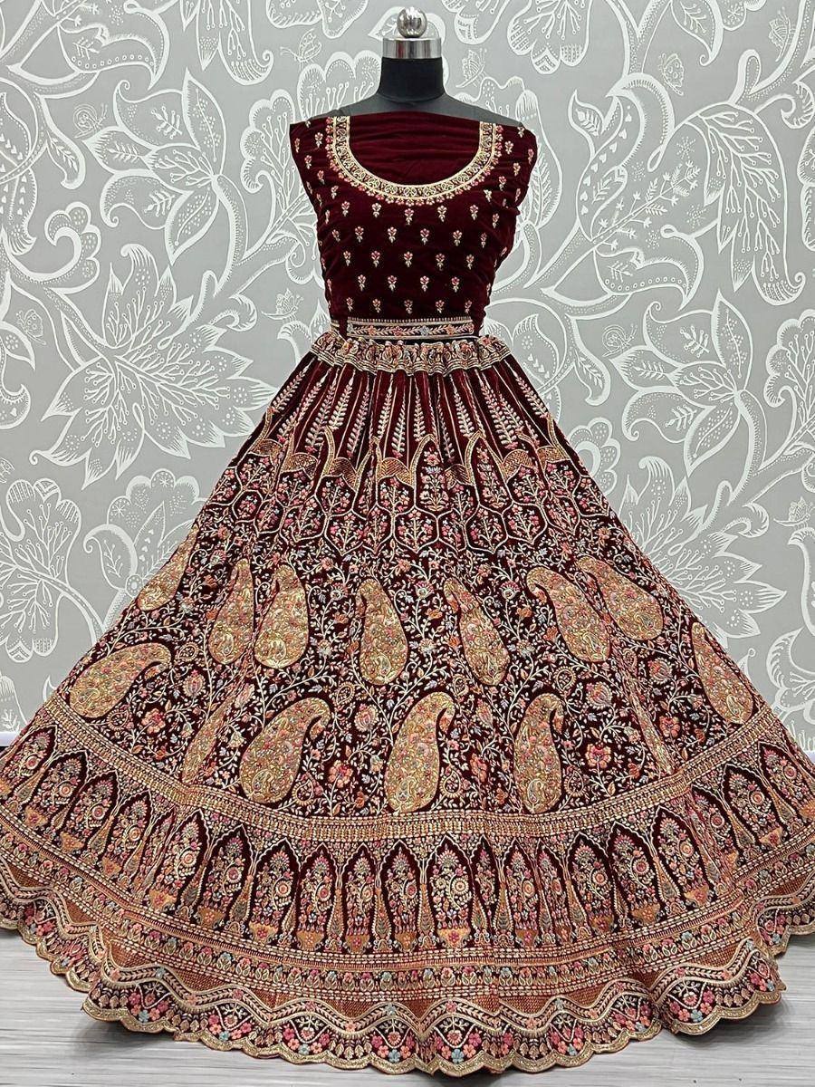 Maroon velvet lehenga choli with intricate gold paisley embroidery, perfect for Indian weddings and festive occasions.