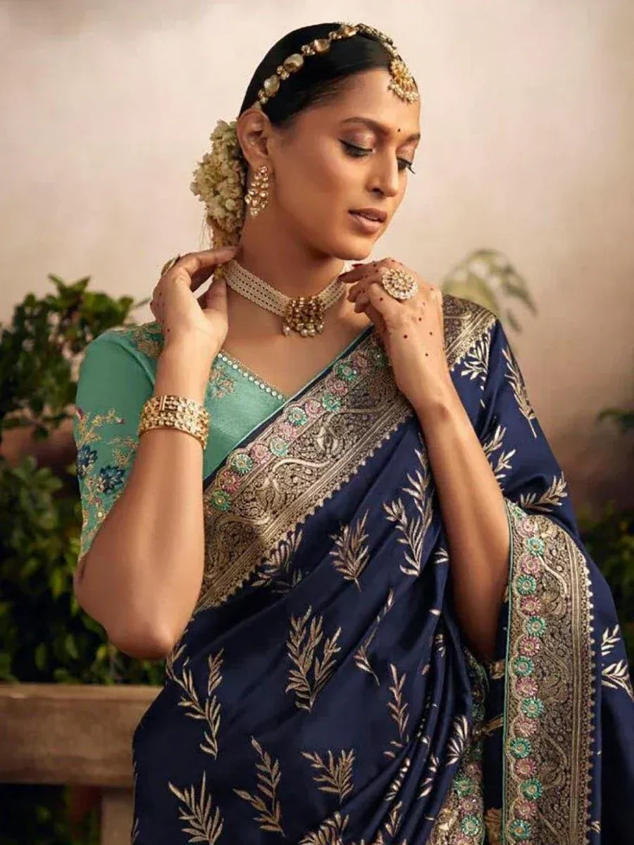 Woman in navy blue embroidered saree with gold leaf motifs, green blouse, and traditional jewelry