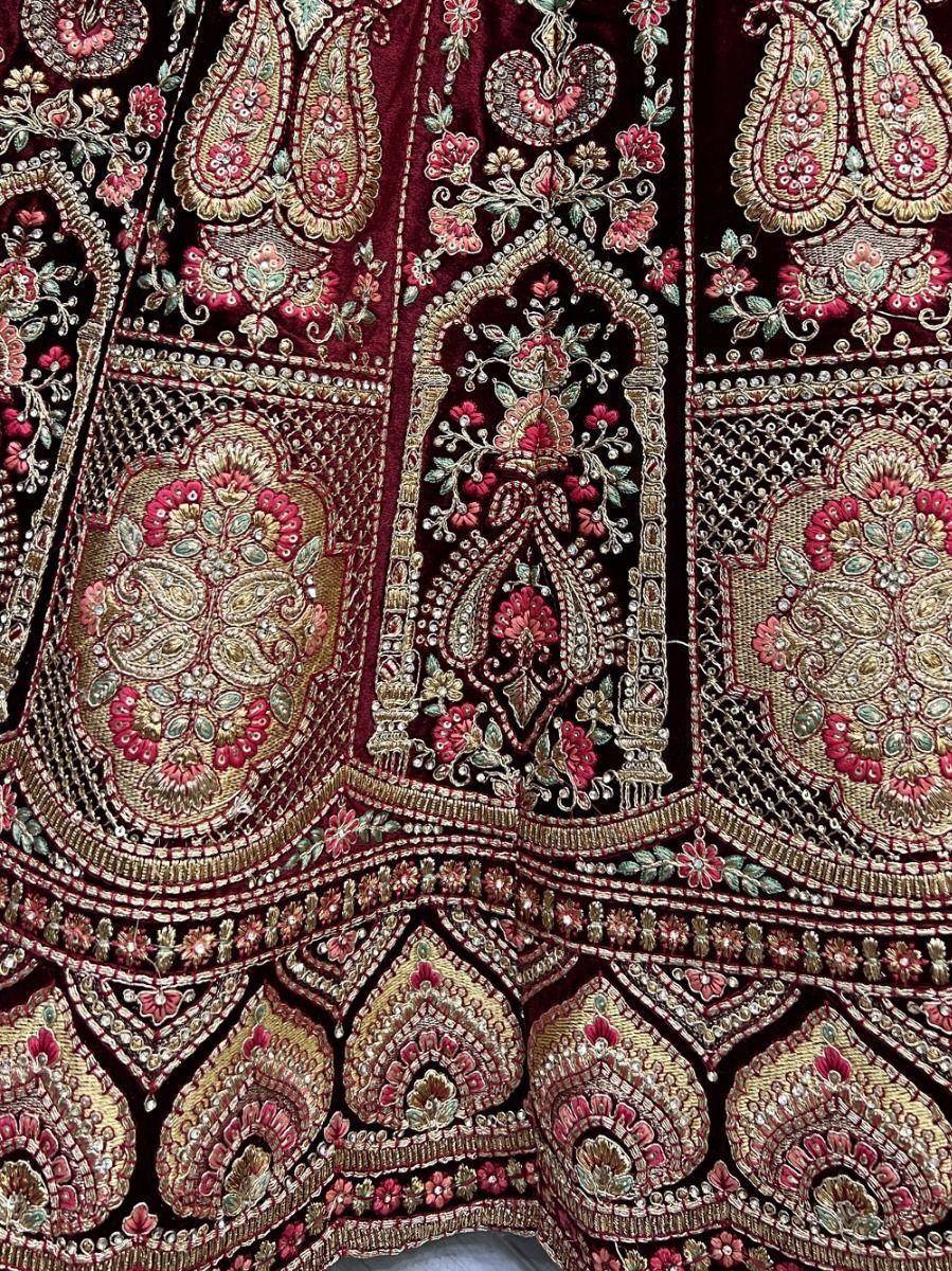 Richly embroidered maroon lehenga with gold and pink floral motifs, perfect for Indian weddings and festive occasions.