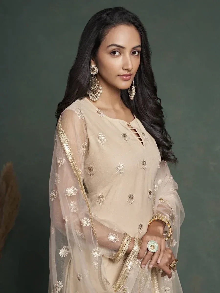 Beige embroidered ethnic kurta with sheer sleeves and gold detailing, paired with statement jewelry