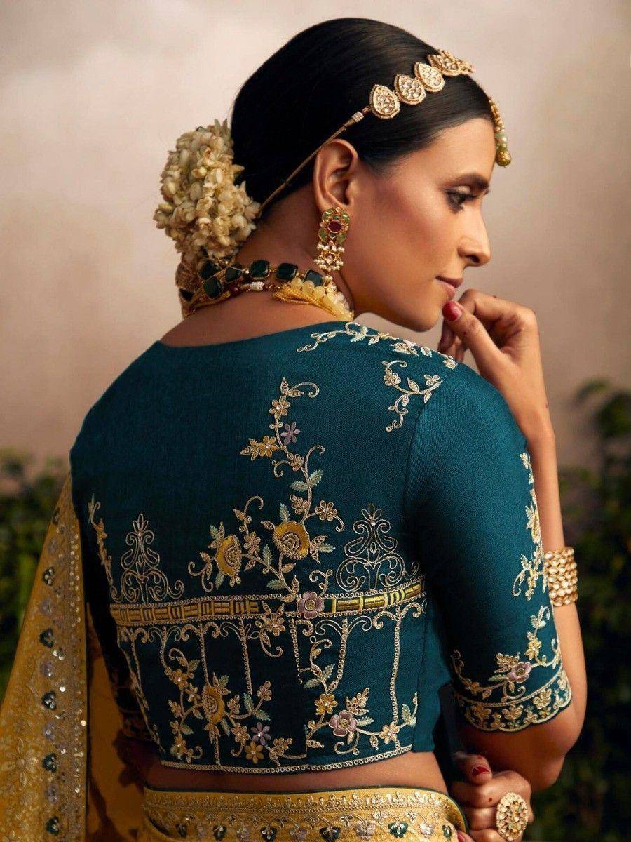 Teal embroidered blouse with gold floral detailing, paired with traditional Indian jewelry and floral hair accessory