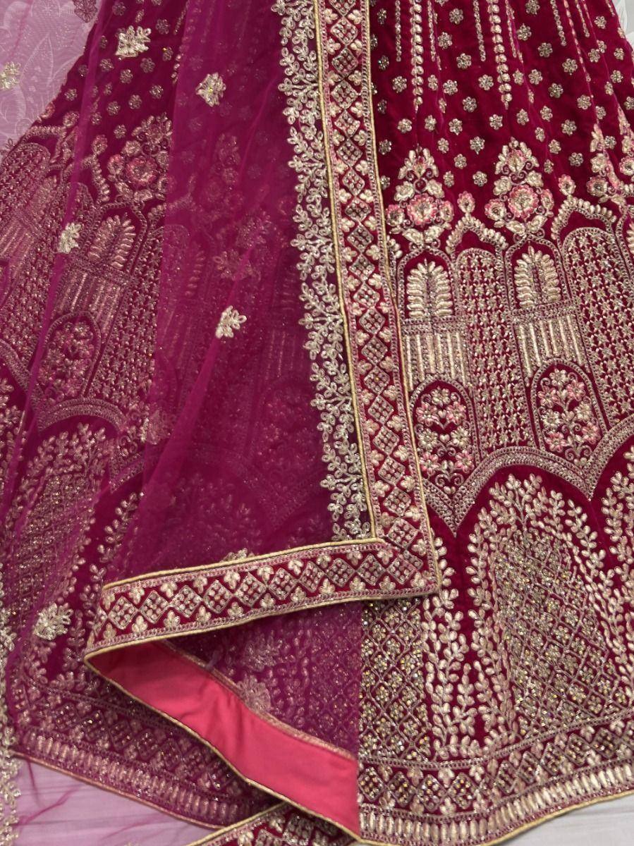 Luxury maroon velvet lehenga choli with intricate gold embroidery and floral motifs, perfect for Indian weddings.